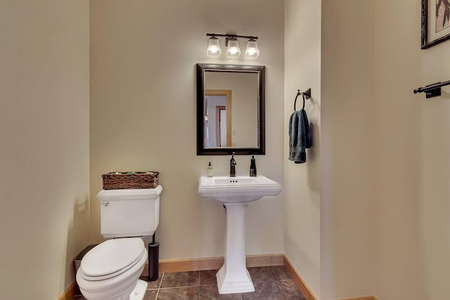 bathroom with baseboards, toilet, and tile patterned flooring