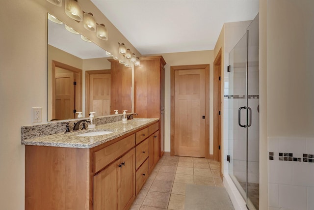 full bath featuring a sink, double vanity, a shower stall, and tile patterned floors