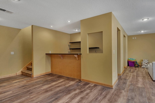 interior space with visible vents, a textured ceiling, stairs, and wood finished floors