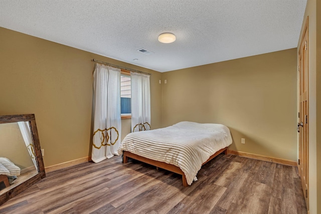 bedroom featuring visible vents, baseboards, and wood finished floors