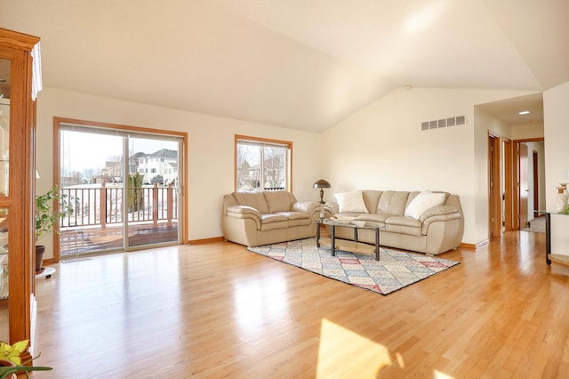 living area with light wood finished floors, visible vents, baseboards, and vaulted ceiling