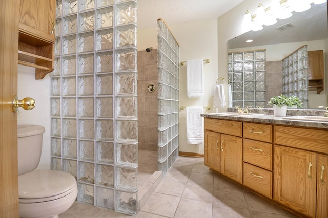 bathroom featuring tile patterned floors, a walk in shower, toilet, and a sink