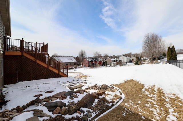 snowy yard with a deck, stairs, and a residential view