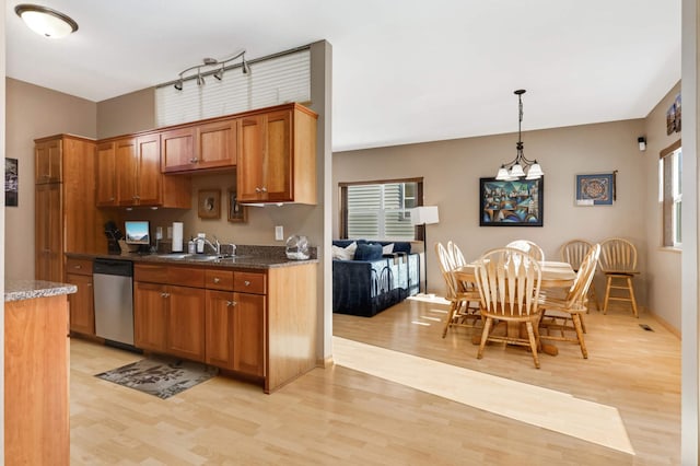 kitchen featuring brown cabinets, a sink, light wood finished floors, dishwasher, and hanging light fixtures