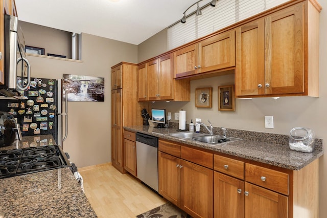 kitchen featuring brown cabinetry, baseboards, a sink, appliances with stainless steel finishes, and light wood-type flooring