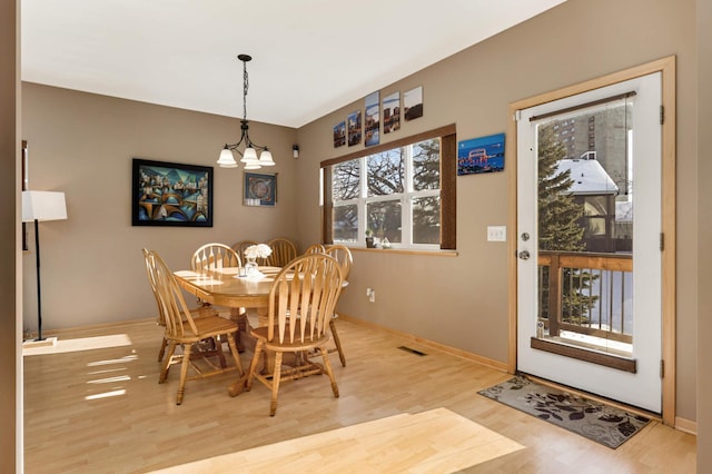 dining area with baseboards, an inviting chandelier, and wood finished floors