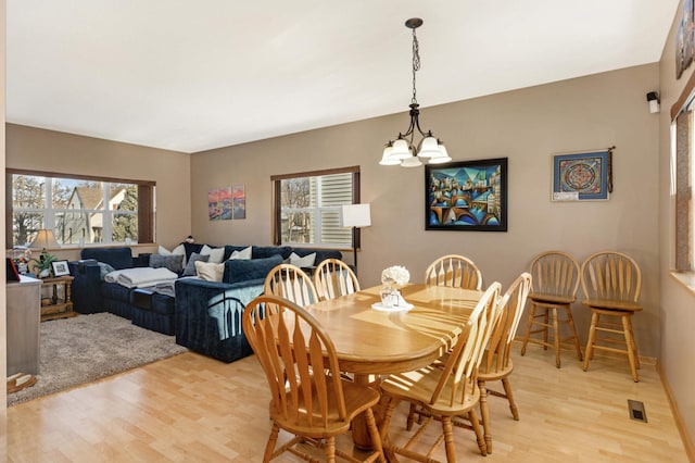 dining area with visible vents, an inviting chandelier, and light wood-style flooring