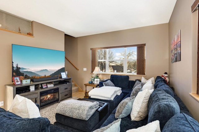 living area featuring stairway and a glass covered fireplace