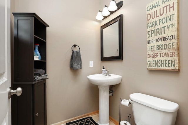 bathroom with toilet, baseboards, and a sink