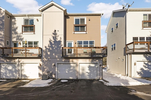 rear view of property featuring an attached garage, driveway, and central AC