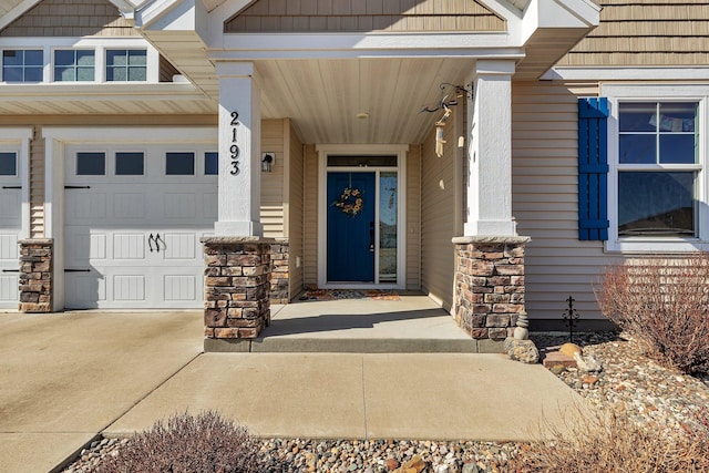 entrance to property with concrete driveway, a garage, and stone siding