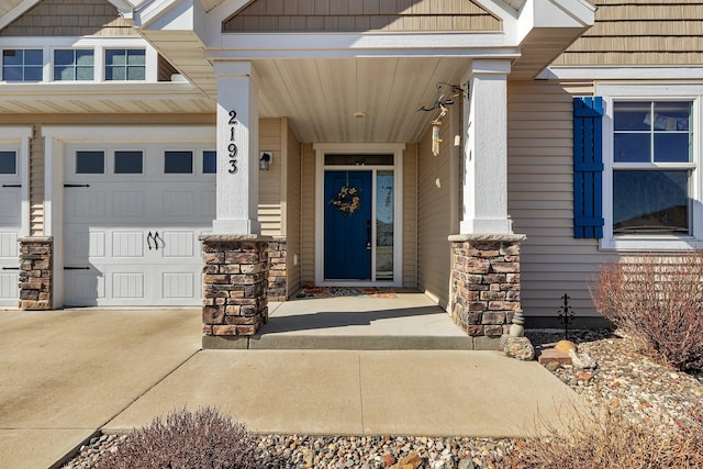 view of exterior entry with stone siding, concrete driveway, and an attached garage