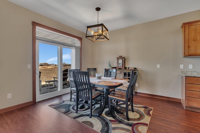 dining space with baseboards, a notable chandelier, and dark wood finished floors