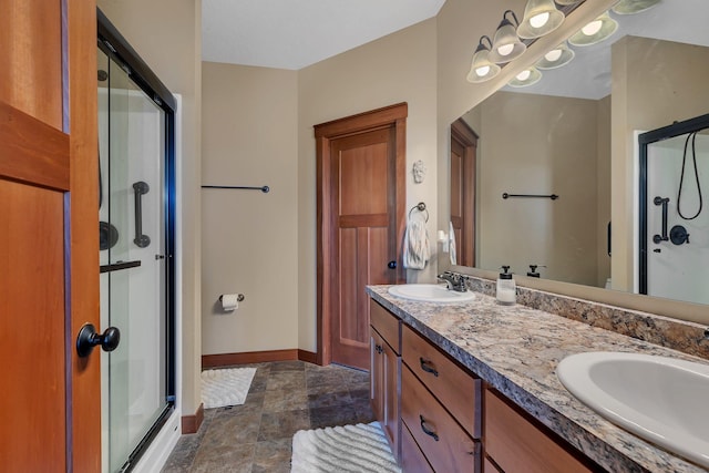 bathroom with double vanity, baseboards, a stall shower, and a sink