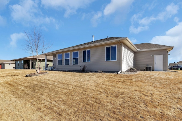 rear view of property with cooling unit and a lawn