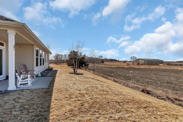 view of yard with a rural view and a patio area