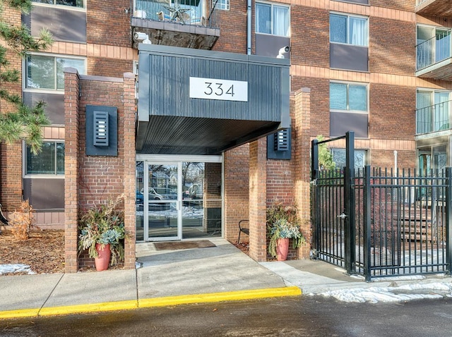 entrance to property featuring brick siding and fence