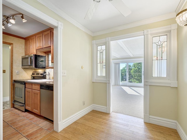 kitchen with light wood-style flooring, baseboards, appliances with stainless steel finishes, and ornamental molding