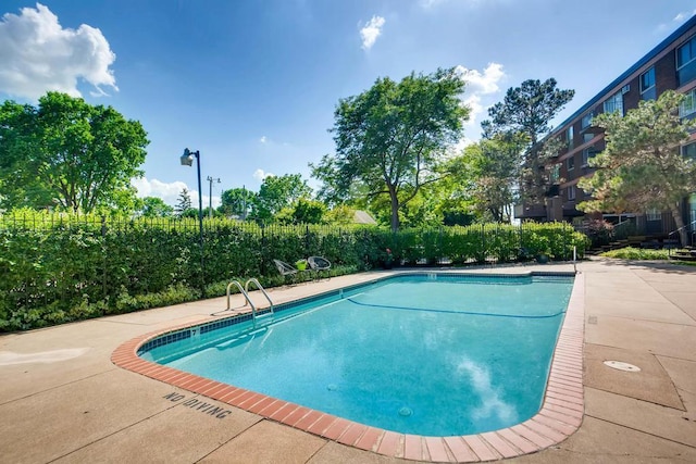 community pool with a patio and fence