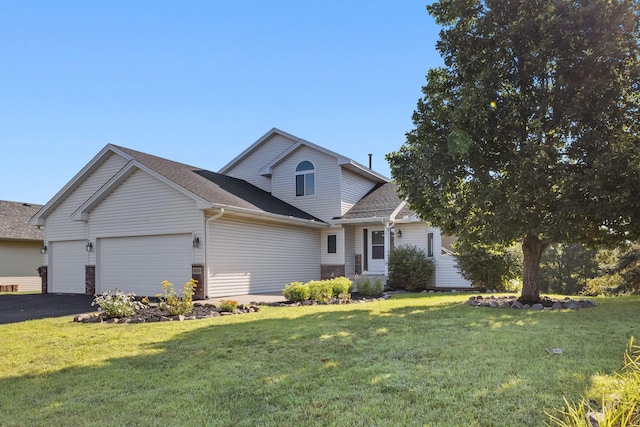 traditional-style home with aphalt driveway, a garage, a front yard, and roof with shingles