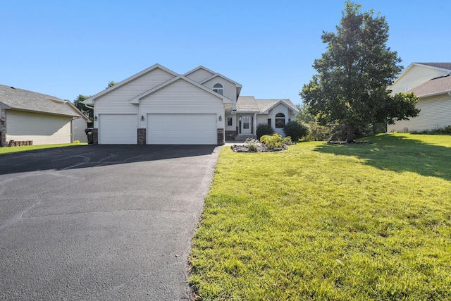 traditional-style home with aphalt driveway, stone siding, an attached garage, and a front yard