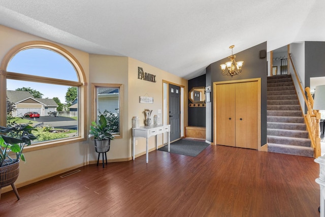 entryway featuring visible vents, stairway, vaulted ceiling, an inviting chandelier, and wood finished floors