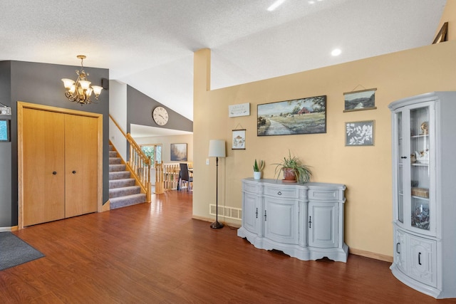 entryway with visible vents, wood finished floors, lofted ceiling, a chandelier, and stairs