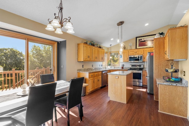 kitchen with light stone counters, dark wood finished floors, a center island, stainless steel appliances, and vaulted ceiling