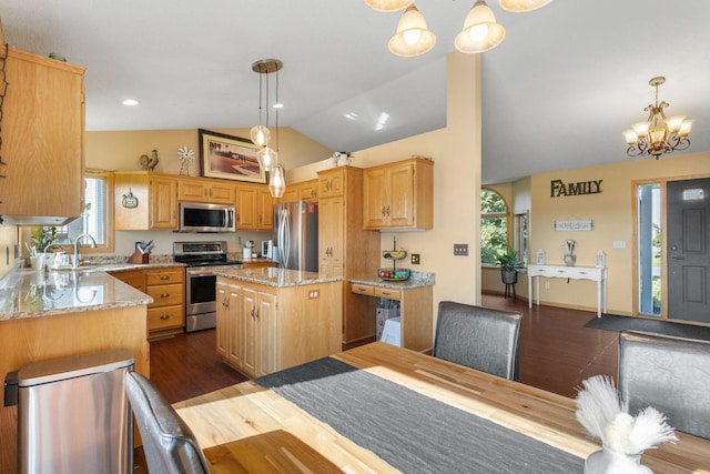 kitchen with light stone countertops, a kitchen island, appliances with stainless steel finishes, and a chandelier