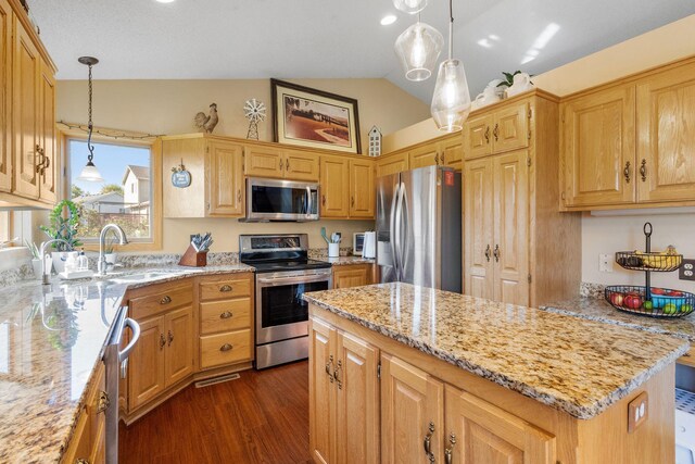 kitchen featuring light stone countertops, a kitchen island, lofted ceiling, a sink, and stainless steel appliances