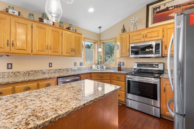 kitchen with dark wood-type flooring, appliances with stainless steel finishes, light stone countertops, vaulted ceiling, and hanging light fixtures