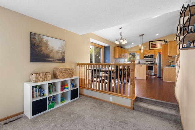 rec room with lofted ceiling, visible vents, dark carpet, and a chandelier