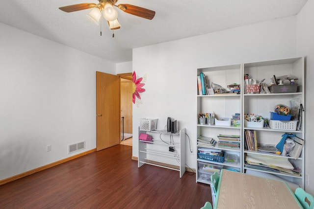 interior space with visible vents, a textured ceiling, wood finished floors, baseboards, and ceiling fan