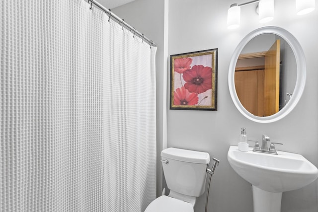 full bathroom featuring curtained shower, toilet, and a sink