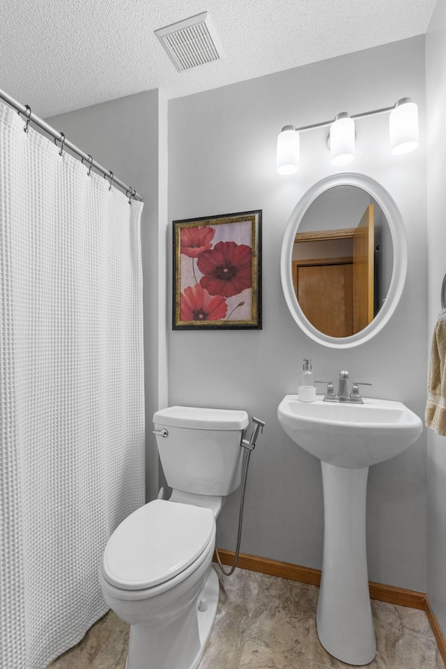 full bath featuring baseboards, visible vents, a sink, a textured ceiling, and toilet