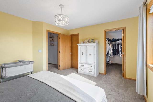 bedroom with light carpet, a closet, baseboards, a chandelier, and a spacious closet