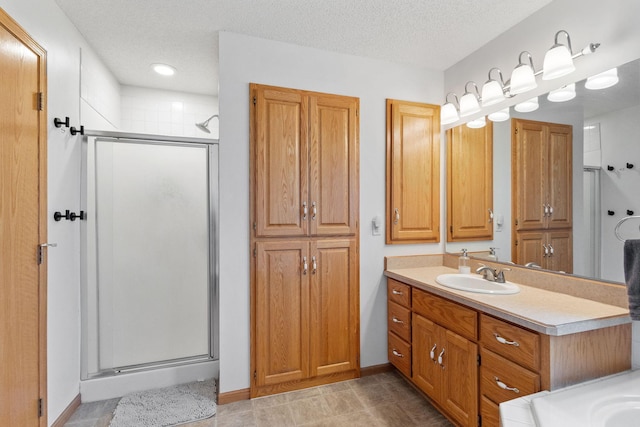 bathroom with a shower stall, a textured ceiling, vanity, and baseboards