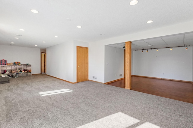 finished below grade area featuring visible vents, recessed lighting, carpet floors, rail lighting, and baseboards