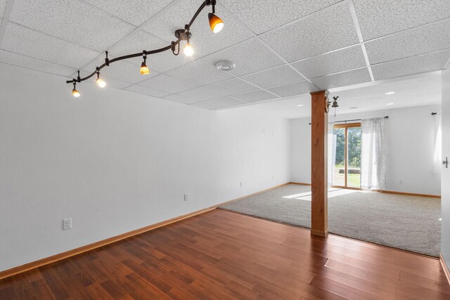 spare room with track lighting, a paneled ceiling, baseboards, and wood finished floors