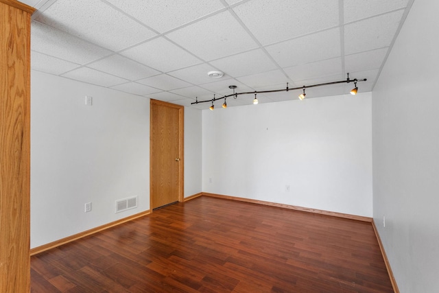 spare room featuring visible vents, wood finished floors, baseboards, rail lighting, and a paneled ceiling