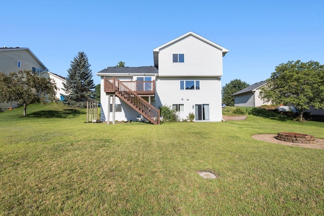 back of property with a deck, stairway, a yard, and a fire pit