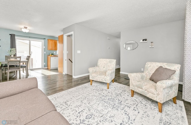 living area with a textured ceiling, baseboards, and wood finished floors