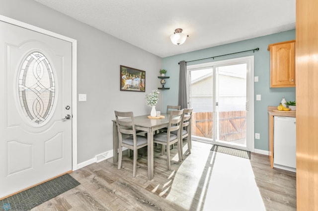 dining area with light wood finished floors, visible vents, and baseboards