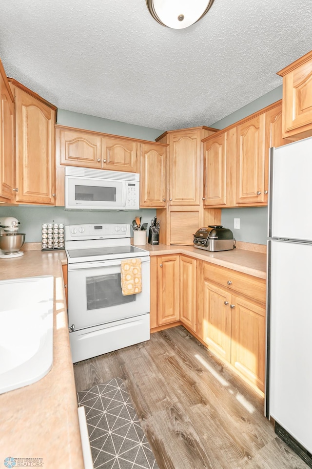 kitchen featuring white appliances, light countertops, and wood finished floors