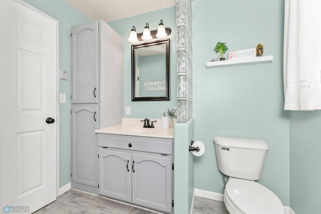 bathroom with vanity, toilet, and baseboards