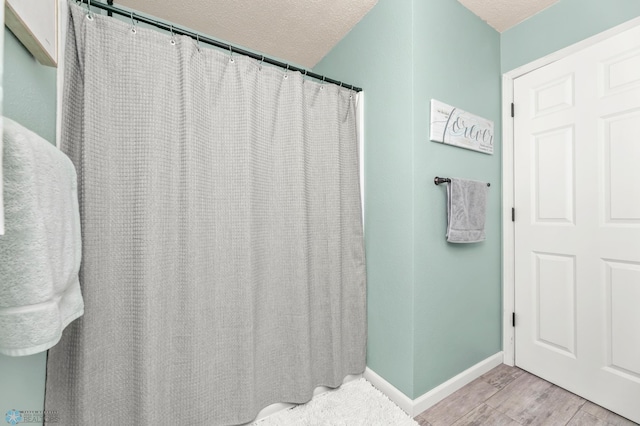 full bathroom featuring wood finished floors, baseboards, and a textured ceiling