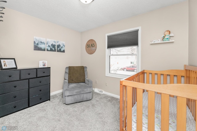 carpeted bedroom featuring visible vents, a textured ceiling, a crib, and baseboards