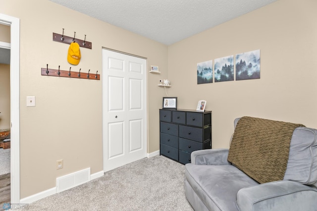 living area featuring baseboards, visible vents, a textured ceiling, and carpet