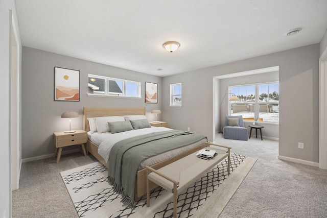 bedroom with light carpet, a textured ceiling, and baseboards