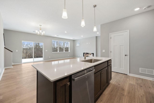 kitchen featuring visible vents, a sink, light countertops, stainless steel dishwasher, and light wood-type flooring